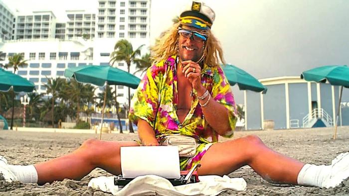 The Beach Bum movie: Moondog (Matthe McConaughey) sits on the beach with a typewriter