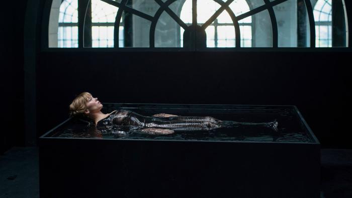 The Beast: Léa Seydoux lays in a bath wearing black and surrounded by darkness apart from a window above