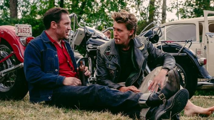 The Bikeriders Movie: Tom Hardy and Austin Butler sit next to their motorcycles, talking