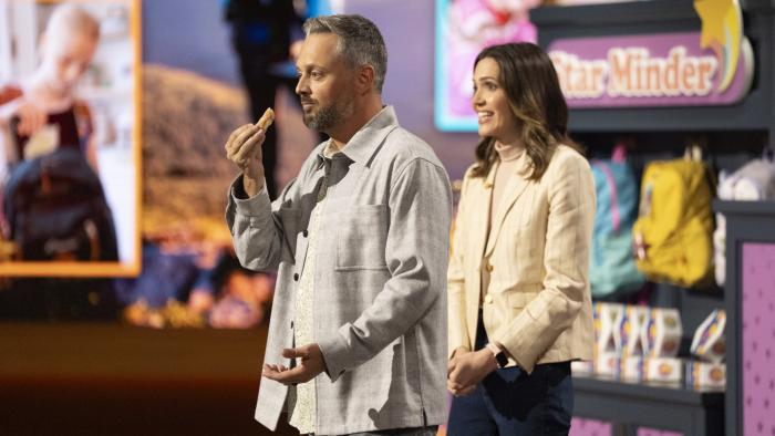 The Breadwinner movie: Nate Bargatze holds a donut next to a smiling Mandy Moore while presenting the Starminder product in front of Shark Tank panel