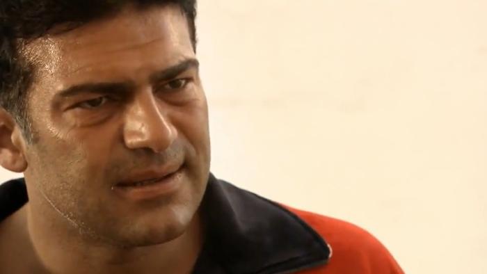 The Business: Man in a red jacket with a concerned expression against a plain background