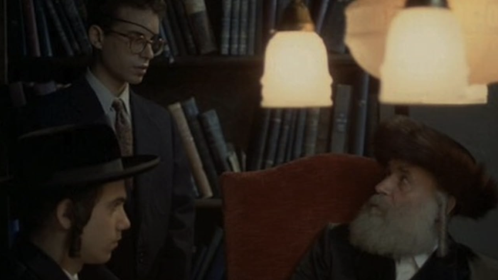 The Chosen: A young Jewish teen stands and speaks to a Rabbi sitting in a chair with a young Orthodox Jewish teen beside him
