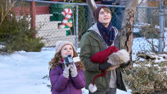 The Christmas Chronicles movie: Kate and Teddy smile up at the sky on a snowy day, Kate holding up a digital camcorder