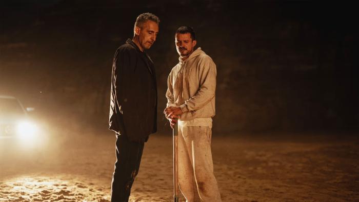 The Cut: Two men stand talking in a desert