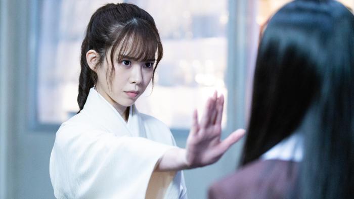 The Divine Protector - Master Salt Begins movie screenshot 1: Master Salt in traditional clothes raises a hand, flat palm, towards Nanako.