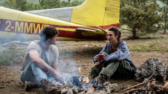 The Dog Stars movie: Jacob Elordi and Margaret Qualley sit next to a campfire near a small plane in a field