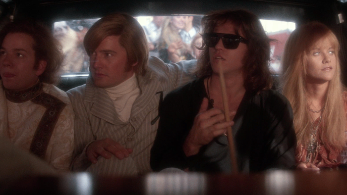 The Doors movie: Three band members of the Doors plus Pam sit inside a car in the backseat