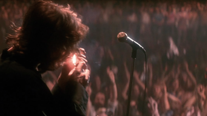 The Doors movie: Jim Morrison lights up a cigarette on stage in front of a huge crowd