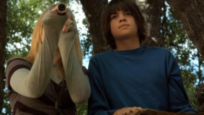 The Gold Retrievers movie: A girl looks through a spyglass and a boy peers out in the same direction, both in the woods