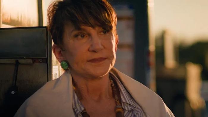 The Nana Project Movie: An older woman with a bright green earring and short brown hair looks ruefully into the distance.