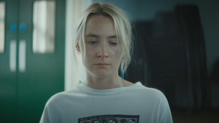 The Outrun: Saoirse Ronan stands inside a meeting hall looking downwards, with green double doors behind her