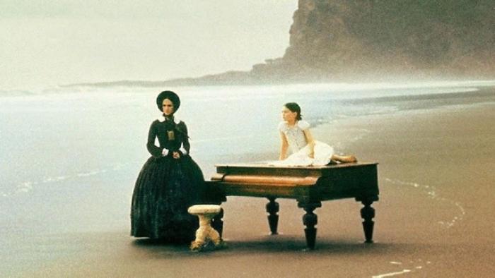 The Piano Movie: Two women with a piano on a misty beach, one seated and one standing.