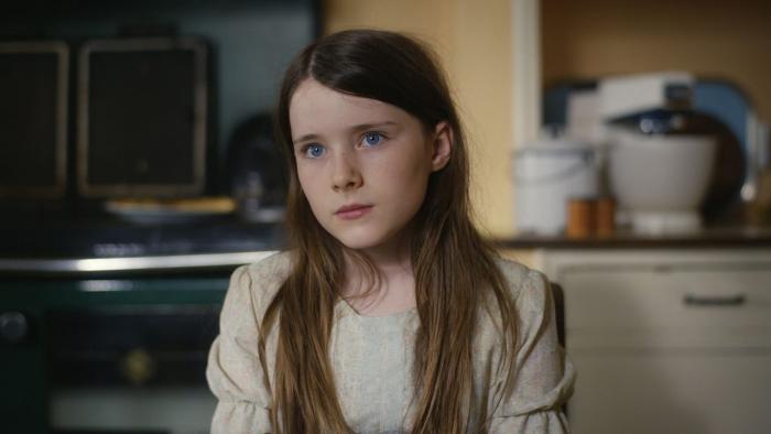 The Quiet Girl: A young girl sits in a kitchen