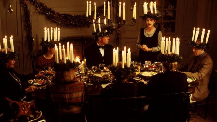 The Ref movie: A White family of 8, each wearing a hat with lit candles in a circle sticking up, sit around a full dining table about to eat