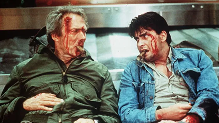 The Rookie (1990) movie: Charlie Sheen right, Clint Eastwood left, each bloodied with cigars in mouths, slumped against an airport baggage carousel