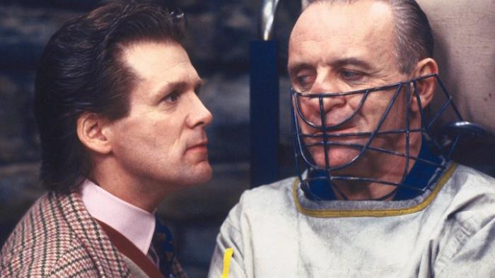 The Silence of the Lambs movie: A man looks closely at Hannibal Lecter whose face is in a cage