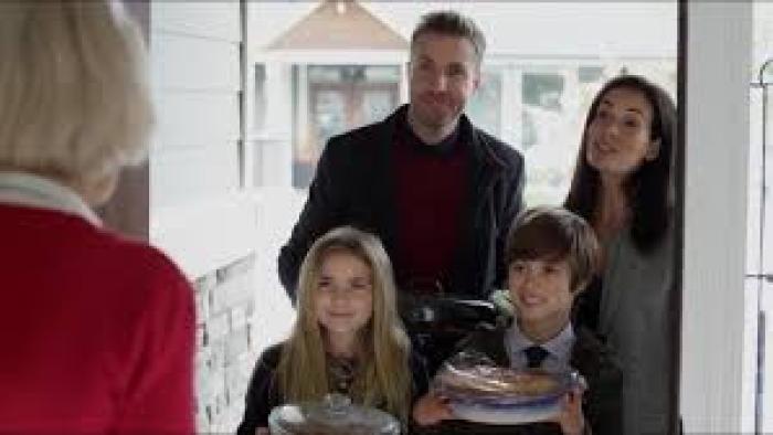 The Family Holiday: A family of four is at the door of a white-haired woman