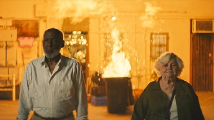 Thelma Movie: Richard Roundtree and June Squibb walk away as a trash can explodes in the background