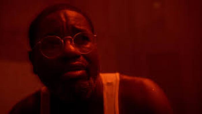 The Mill Movie scene 2: A Black man with glasses with red background