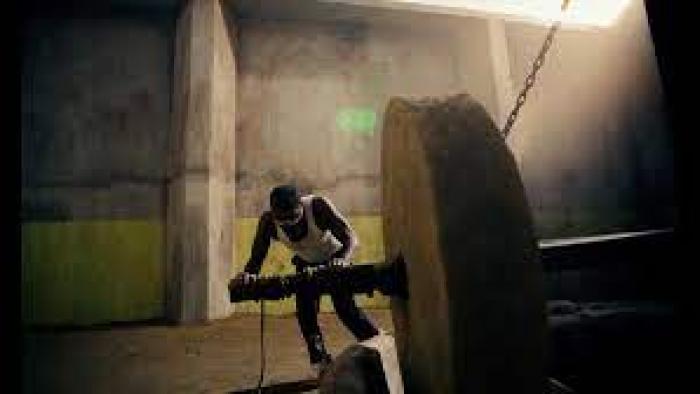 The Mill Movie scene 3: A Black man in a tank top pushes a huge wheel