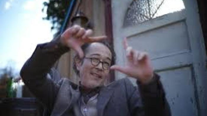 The Parades: An Asian man gestures outside