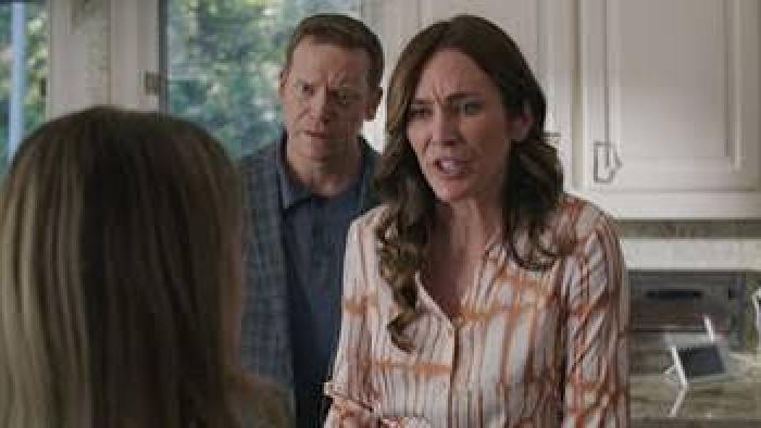 The Seemingly Perfect Family: Woman and man in a kitchen, looking concerned at another person.