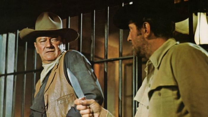 The Sons of Katie Elder: Two White men in a jail cell, one holds up a dagger.