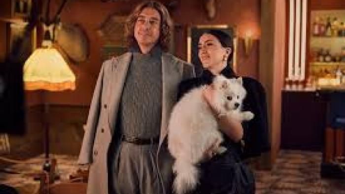 The Storm movie: White man and woman smiling indoors, holding a fluffy white dog.
