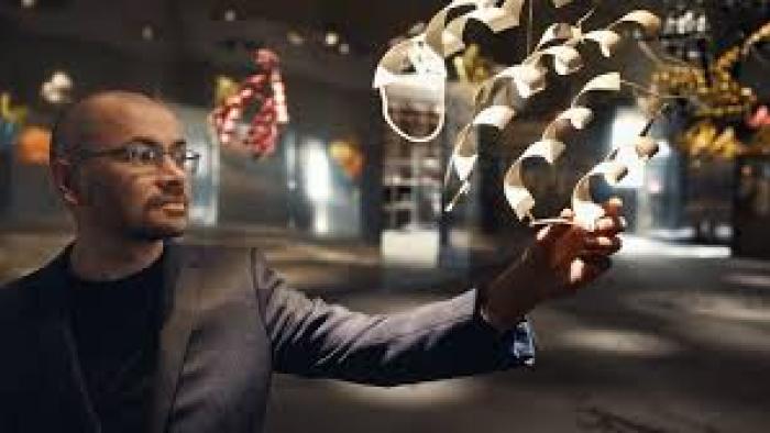 The Thinking Game Movie:  Man in a suit interacting with digital graphics in a dimly lit room.