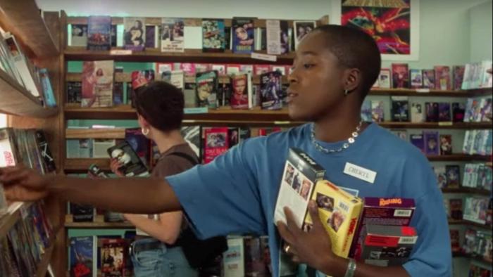 The Watermelon Woman: A person working in a video rental store stacking shelves. 