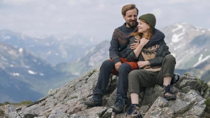 Too Old for Fairy Tales 2: A lady and a man sit together on the top of a mountain in an embrace
