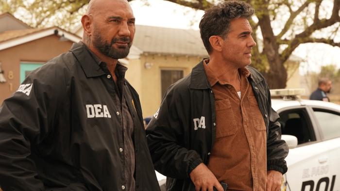 Trap House Movie: Ray (Dave Bautista) and Andre (Bobby Cannavale), wearing black DEA jackets, survey a crime scene