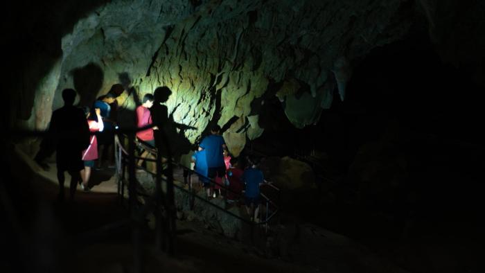 The Trapped 13 - How We Survived the Thai Cave: Thai boys illuminated by torchlight in an otherwise pitch black cave.