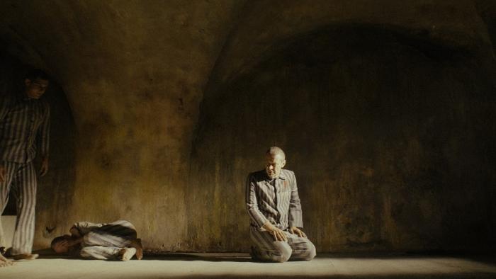 Triumph of the Heart movie: Marcin Kwaśny kneels inside Auschwitz