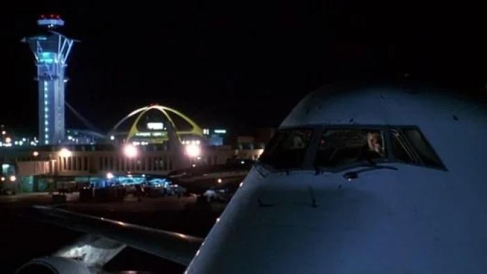 Turbulence: Plane a night on airport runway with buildings and lights in background