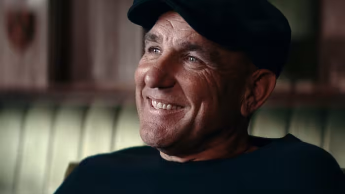 Untold UK -- Vinnie Jones: Vinnie Jones smiling in a cap, seated in warmly lit room