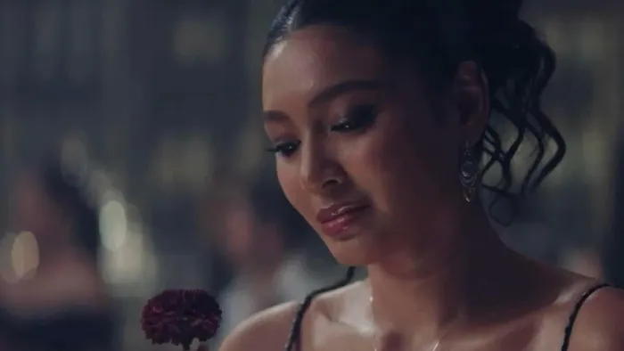 Uninvited movie: Filipino woman with hair up wears silver earrings while looking at a flower in front of her