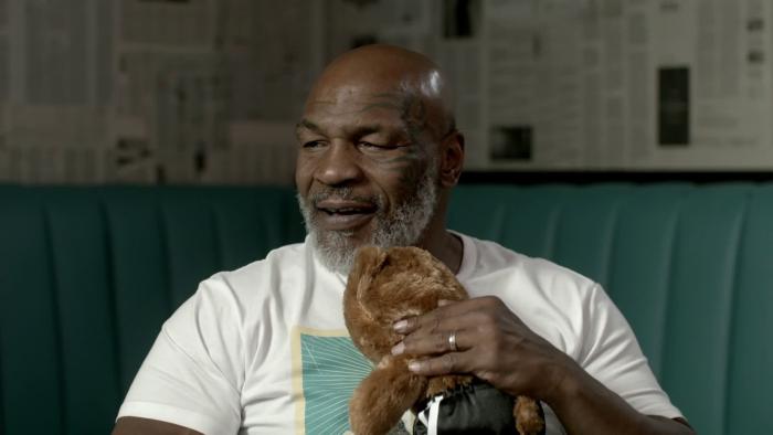 Unstuffed: A Build-a-Bear Story: Boxer Mike Tyson is seated holding a small teddy bear.