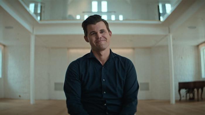 Untold: Chess Mates movie: Magnus Carlsen sits and smiles in a large white room