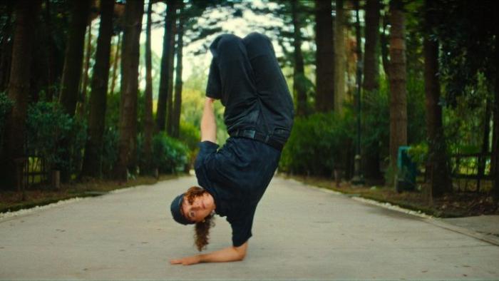 Untold Raygun: Breaking Badly movie: Raygun balances on one arm on a tree-lined path.