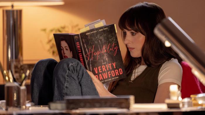 Verity movie: Anne Hathaway reads a book by author Verity Crawford in a cozy setting surrounded by soft lighting