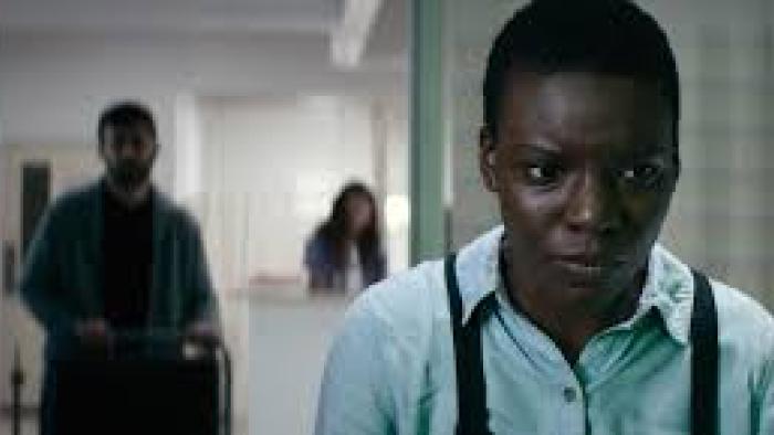 Weathering: A Black woman walk away from blurred people
