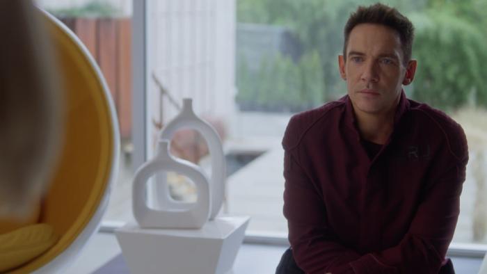 Wifelike: Jonathan Rhys Meyers sits wearing dark clothing, looking at someone out of shot.
