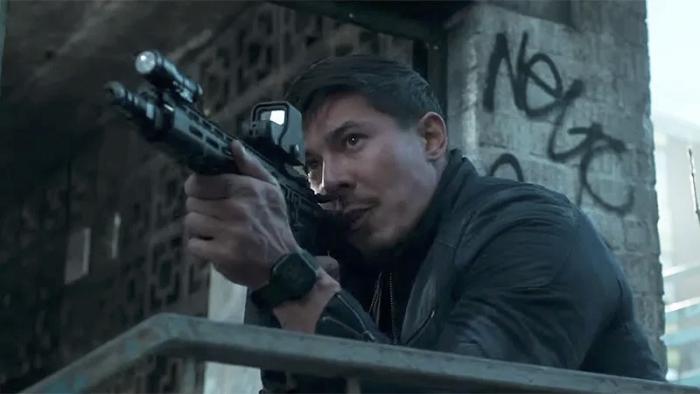 Wildcat: Lewis Tan stands next to a wall covered in graffiti and aims a gun just out of shot