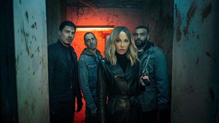 Wildcat: Kate Beckinsale stands in front of a crew including Lewis Tan, Rasmus Hardiker, and Bailey Patrick