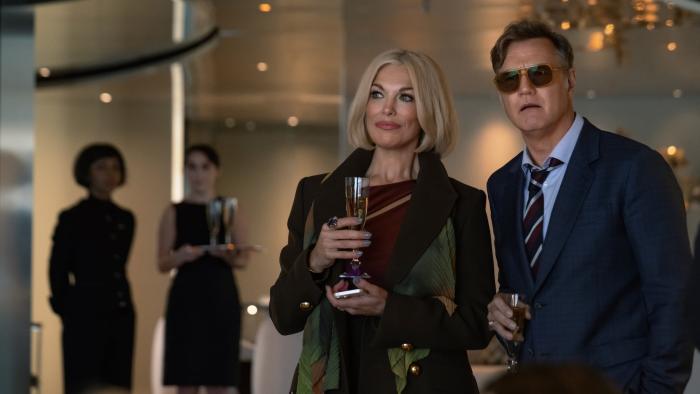 The Woman in Cabin 10: Hannah Waddingham and David Morrissey each hold a glass of champagne at a soiree on a boat