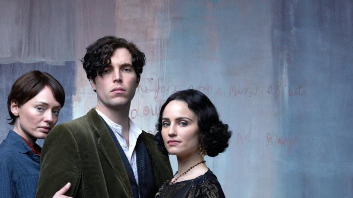 The Laureate: A young White man stares at the camera with a woman either side of him