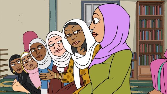 A row of women wearing headscarves lean forward in a row. They stare at a woman at the end, in a green top and pink headscarf.