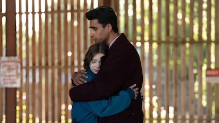  A Good Girl's Guide to Murder: Season 2 TV show screenshot: Man and woman hugging in front of a sunlit fence.
