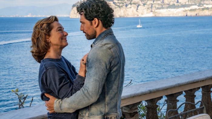 Deceitful Love TV show screenshot: A White man and a White woman embrace while looking into each other's eyes by an ocean harbor